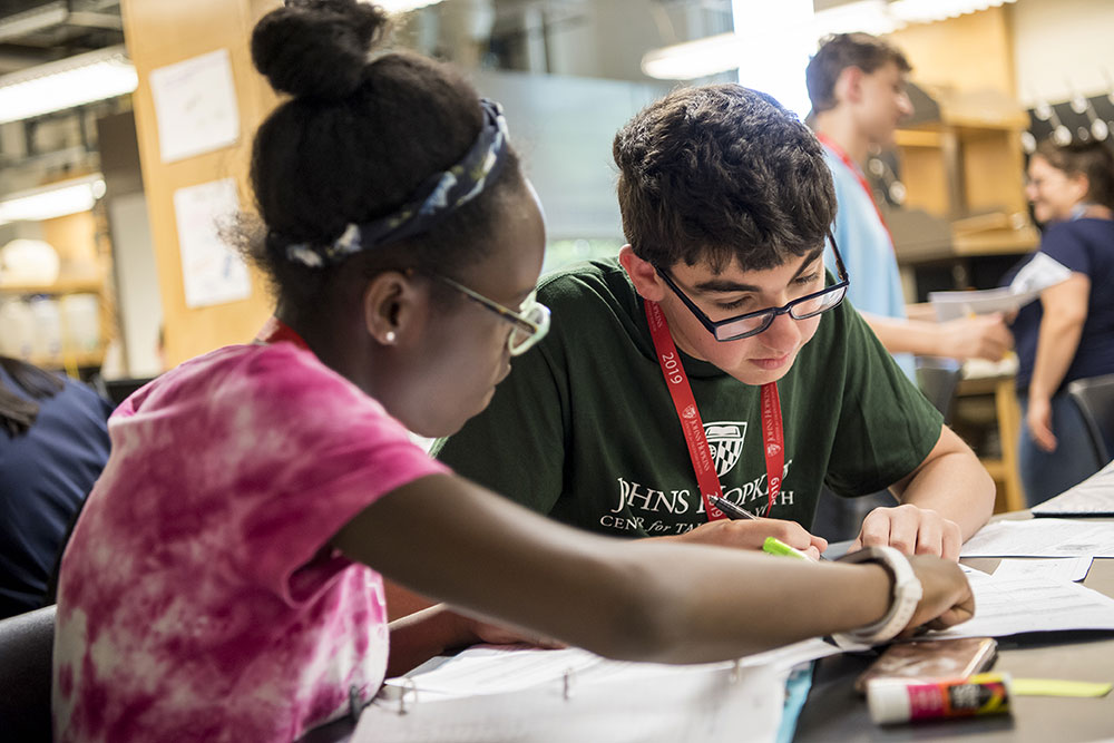 Two CTY students in a classroom, sitting at a desk, and working on a paper together