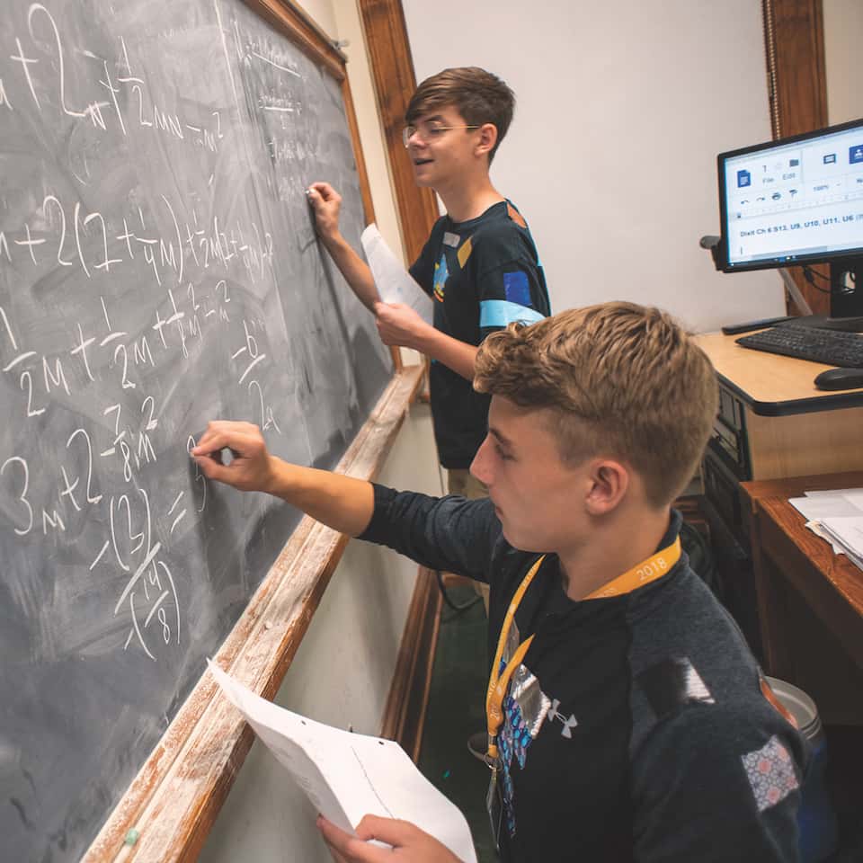 Two CTY students writing on a chalkboard