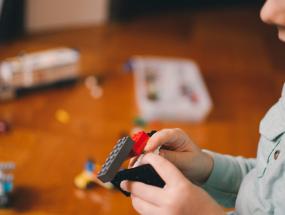 Image of a kid playing with toy building bricks. Photo by Kelly Sikkema on Unsplash