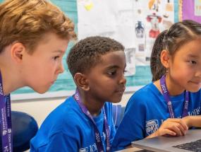 Three young CTY students looking at a laptop