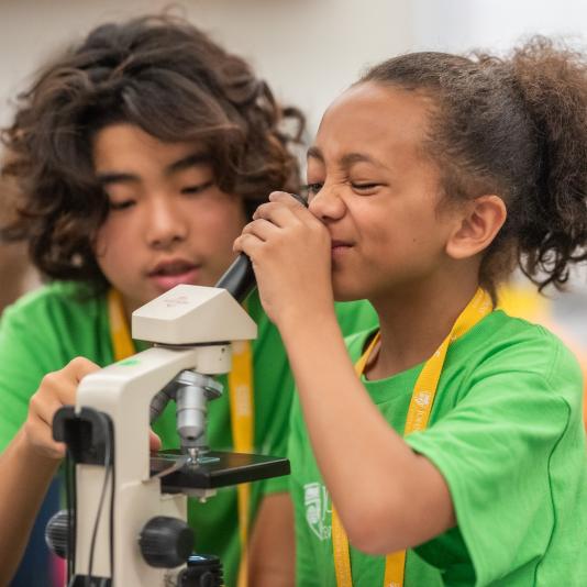 Two students looking into a microscope 