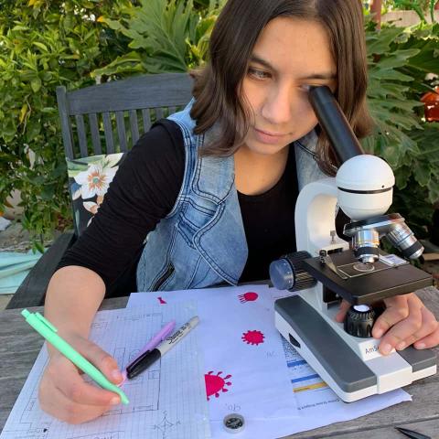 research on teaching and learning of nature of science Online Programs student looking through microscope