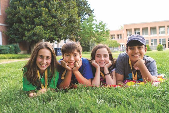 Four CTY students lying in the grass smiling