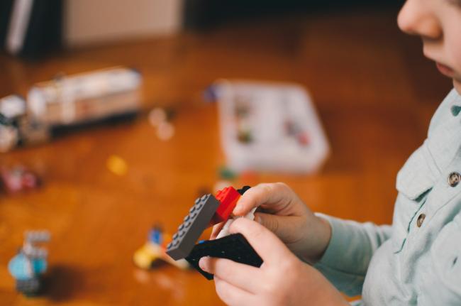 Image of a kid playing with toy building bricks. Photo by Kelly Sikkema on Unsplash