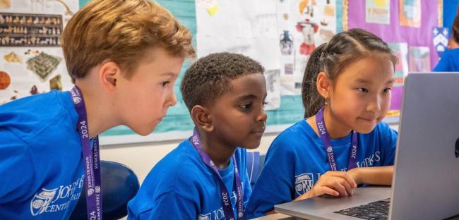 Three young CTY students looking at a laptop